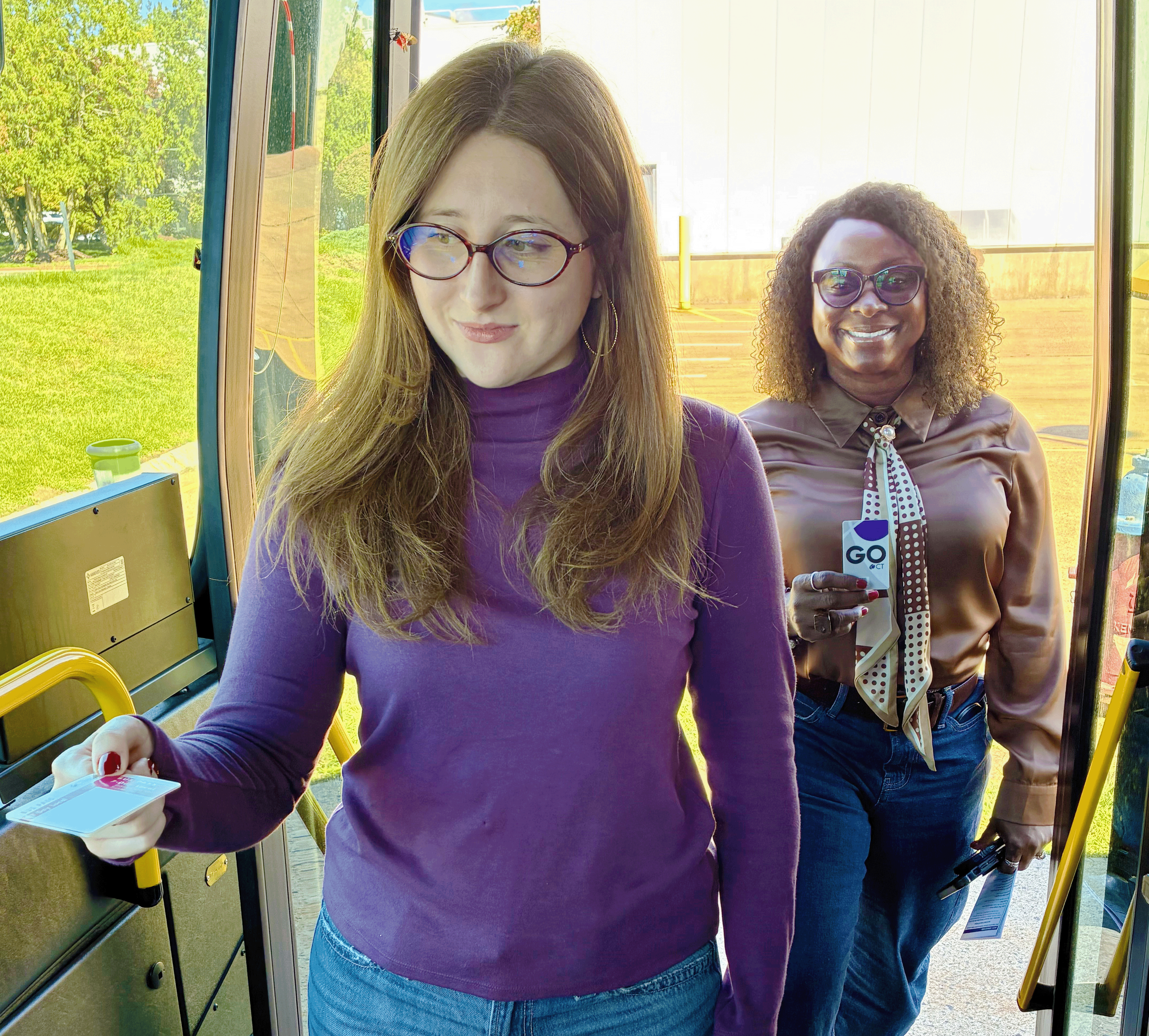 Two women board a bus with fare cards in their hands